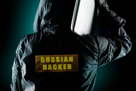 Russian hacker with a laptop on his shoulder on a dark background. The concept of risk of Russian...
