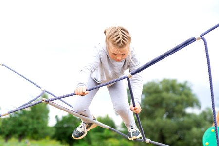 Little girl climbing in an adventure park. The girl loves to climb in the adventure of the rope...