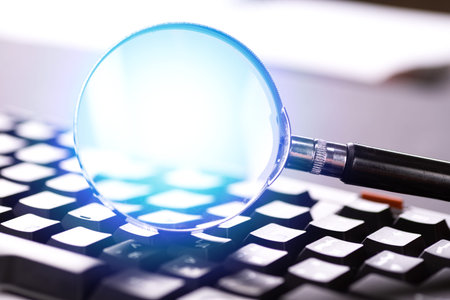 Magnifying glass on the keys of a black computer keyboard.