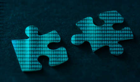 Binary code on two puzzle pieces on a black background.の写真素材