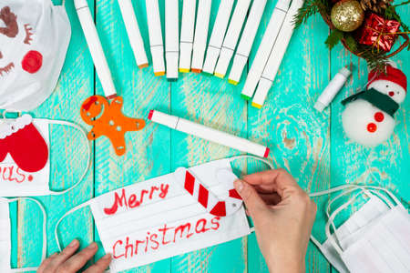 Celebrating Christmas amid a pandemic. We draw pictures and inscriptions on medical masks. Getting ready for Christmas. Positive use of medical masks during a pandemic.の写真素材