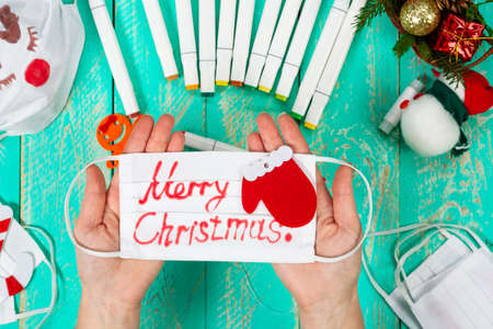 Celebrating Christmas amid a pandemic. We draw pictures and inscriptions on medical masks. Getting ready for Christmas. Positive use of medical masks during a pandemic.の写真素材