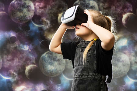Cute teenage girl using VR glasses on colorful background with blank space for textの写真素材