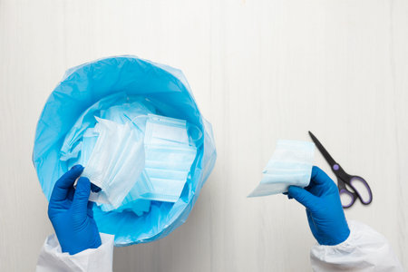 Hands with scissors cut through the medical mask.の写真素材