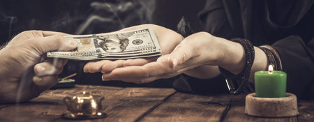 A fortune teller or oracle takes money for their work. Fortune telling by hand, geromancy. Psychic readings and the concept of clairvoyance.の写真素材