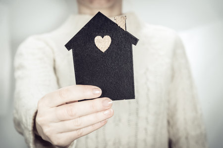 A woman is holding a mock-up of a dark house. Family, real estate and insurance concept.の写真素材
