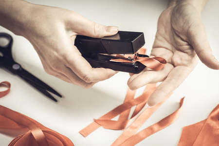 Health care and medicine concept. AIDS awareness. Female hands make red awareness ribbons with a red ribbon and a stapler. World aids day.の写真素材