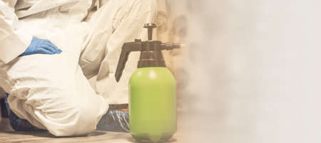 Spray bottle with pesticides close-up. An exterminator in work clothes sprays pesticides from a spray bottle. Fight against insects in apartments and houses. Disinsection of premises.の写真素材