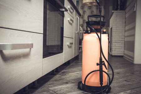 Spray gun with pesticides close-up. An exterminator in work clothes sprays pesticides from a spray bottle. Fight against insects in apartments and houses. Disinsection of premises.の写真素材