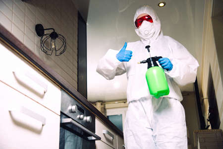 Exterminator in work clothes showing thumbs up. Fight against insects in apartments and houses. Disinsection of premisesの写真素材