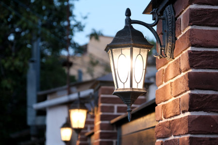 The dark street is illuminated by street lamps. Vintage lantern on a brick wall in the evening.の写真素材