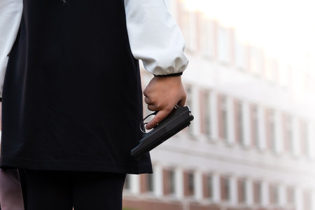 Firearms at school. A teenager with a gun on the background of the school. The girl goes to school with a gun. school violence.の写真素材