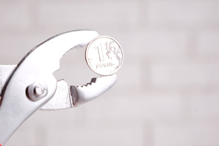 One Russian ruble and pliers, one Russian ruble coin in metal pliers, Russia crisis concept.の写真素材