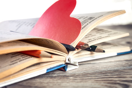 Book and heart shaped bookmark on wooden tableの写真素材