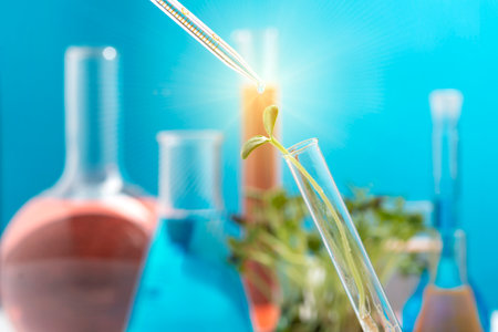 Green sprout in a chemical test tube and a chemical pipette with a drop of a transparent liquid on a blue background.の写真素材