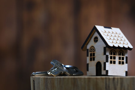 Wooden house model with copy space on the left with keys. The concept of building or buying a houseの写真素材
