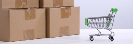 Lots of cardboard boxes on the table and a mini shopping cart. The concept of ordering goods through onlineの写真素材