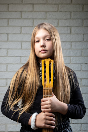 Beautiful blonde woman with long unfolded arms holds a guitar in her hands.の写真素材
