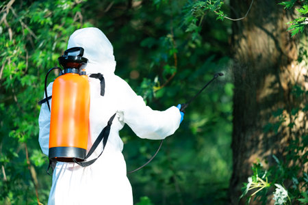 A worker sprays pesticides on trees outdoors, close-up. Pest controlの写真素材