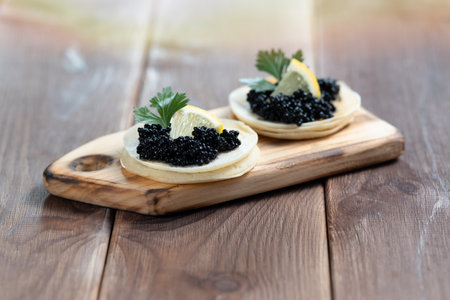 Black sturgeon caviar on pancakes on a wooden plate close-upの写真素材