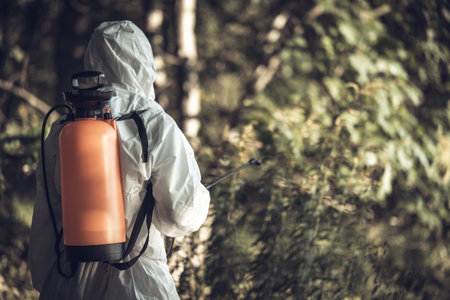 A worker sprays pesticides on trees outdoors. Tree pest control.の写真素材