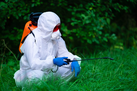 A worker sprays pesticides on trees outdoors. Tree pest control. Insect pest control.
