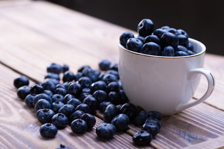Fresh blueberries in a white cup on a wooden tableの写真素材