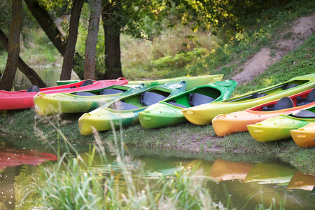 Many canoes of different colors on the river bank before training. Boating on the city riverの写真素材