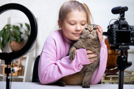 A beautiful blonde -teenage broadcasts live with her cat. Living a broadcast. Ring lamp and camera during a direct broadcast of a video -bloggerの写真素材