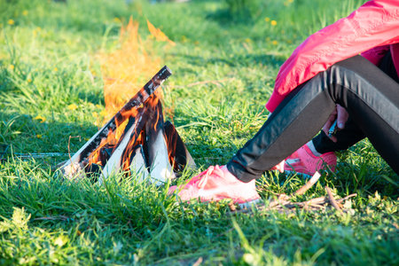 Woman sitting on the grass near a burning fireの写真素材
