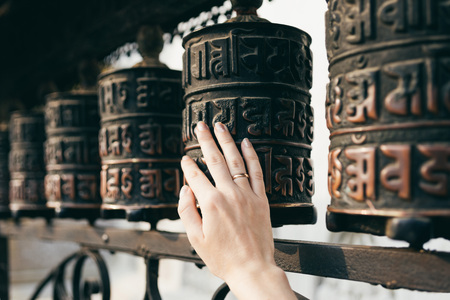 Buddhist prayer drums with close-up mantras.The female hand touches the Buddhist prayer drum, Nepal.The interaction of human energy and the Buddhist prayer drum.the girl turns the prayer drum.の写真素材