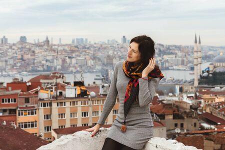 Romantic young woman enjoys a picturesque panoramic view of Istanbul from the roof. Tourist girl on the background of autumn Istanbul.の写真素材