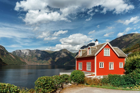 Typical Norwegian red house in the background of a picturesque fjord. Beautiful Norwegian landscape with a red house and atmospheric sky.のeditorial素材