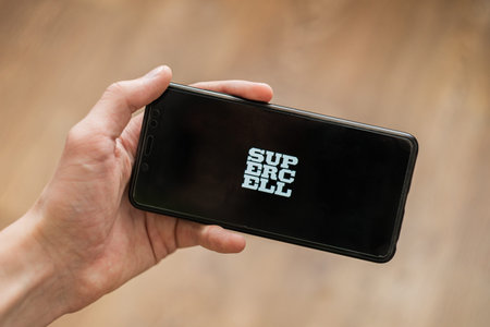 hand holding phone with supercell logo mobile game