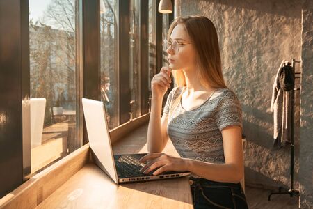 young beautiful girl in a coffee working on a laptop,space for text on the screenの写真素材