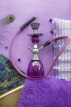 purple hookah with pillows and national fabric out of focus with soft blurring on a purple background with the effect of grain flat layの写真素材