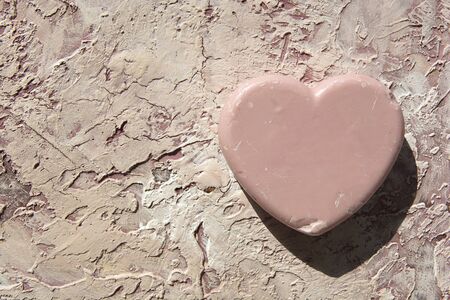 close-up of a heart made of soap on a textural background of pink powder color with soft blur background and noise effectの写真素材