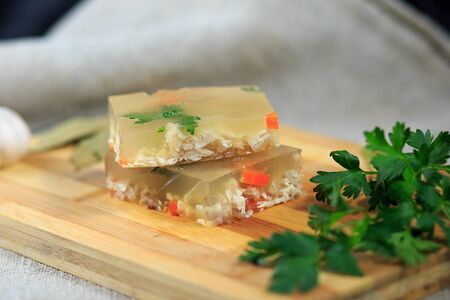 Jellied dish with chicken, carrots and parsley on a wooden boardの写真素材