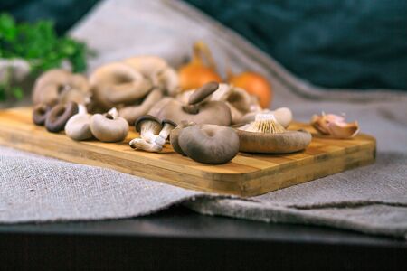 mushrooms of a veshanka and champignons on a wooden board on a tableの写真素材
