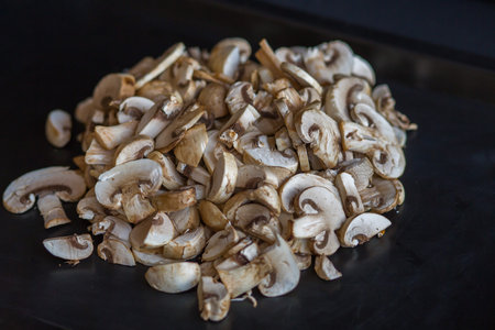 champignon mushrooms raw sliced slices on a table on a black backgroundの写真素材
