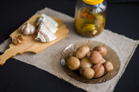 Potatoes baked in their jackets. Potatoes in their skins, bacon, garlic and pickles on the table.の写真素材