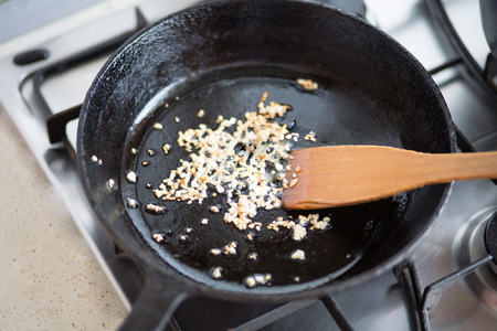 Fried garlic on a black frying pan on a plateの写真素材