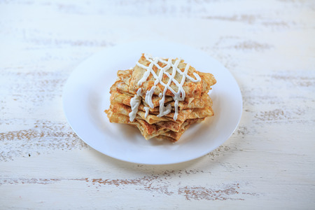 The Russian pancakes with a stuffing on a white plate on a light background. Maslenitsa.の写真素材