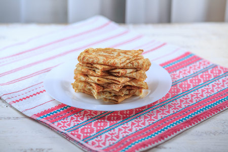The Russian pancakes with a stuffing on a white plate on a light background. Maslenitsa.