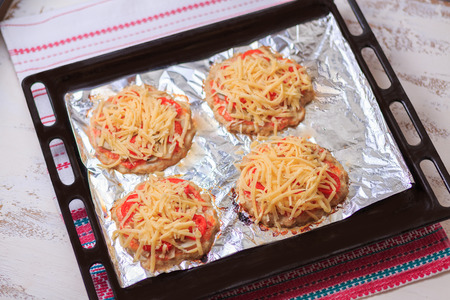 Small cheese and chicken pizza on a foil on a table.の写真素材