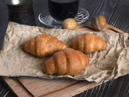 Fresh baked croissants on paper and wooden background. breakfast option, next to a turk and a cup of coffee.の写真素材