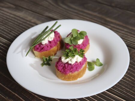 Beautiful sandwiches with pink and white pasta, fresh herbs on a white plate and wooden background.の写真素材