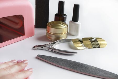 Closeup of female hands filing nails with professional nail file in beauty nail salonor at home. Top viewの写真素材