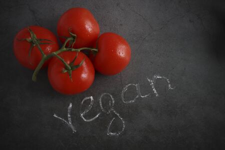 vegetarian food. tomatoes on a dark background. vegan inscription, vignette.の写真素材