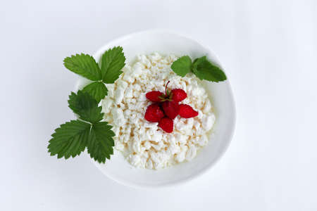 cottage cheese . fresh diet curd homemade in a white plate with ripe strawberries and mint leaf on white background from boards. healthy breakfast optionの写真素材